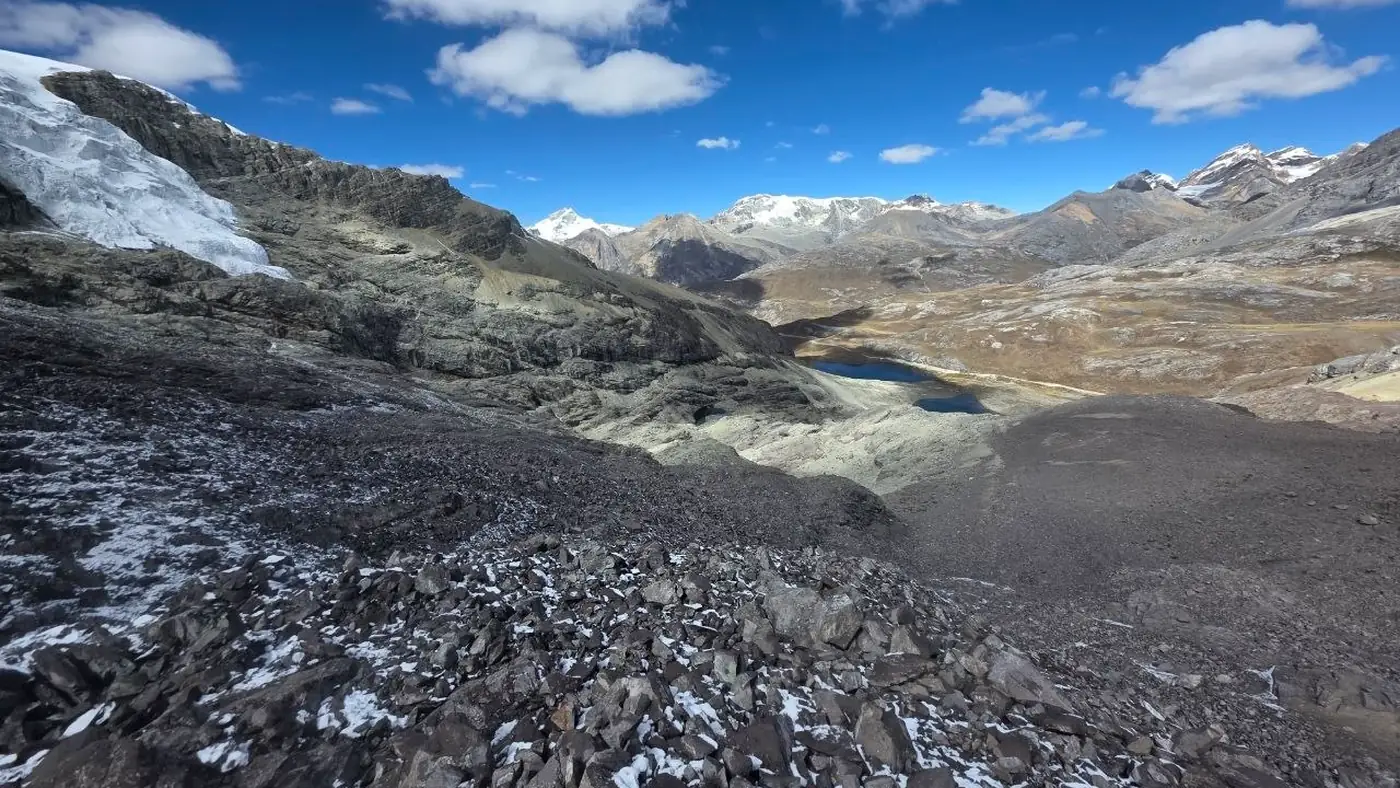 High-mountain surface with dark rock and residual snow, used as a conceptual low-reflectance endpoint