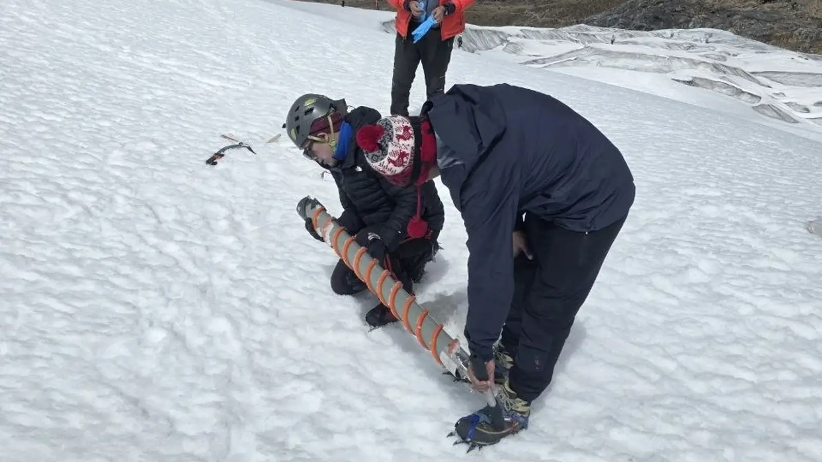 Researcher extracting and documenting a snow sample during glacier fieldwork