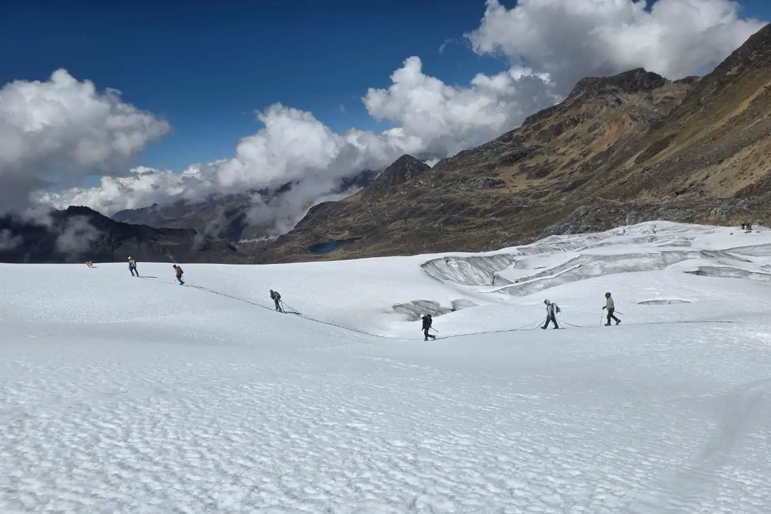 Equipo de campo desplazándose sobre una superficie de nieve en alta montaña