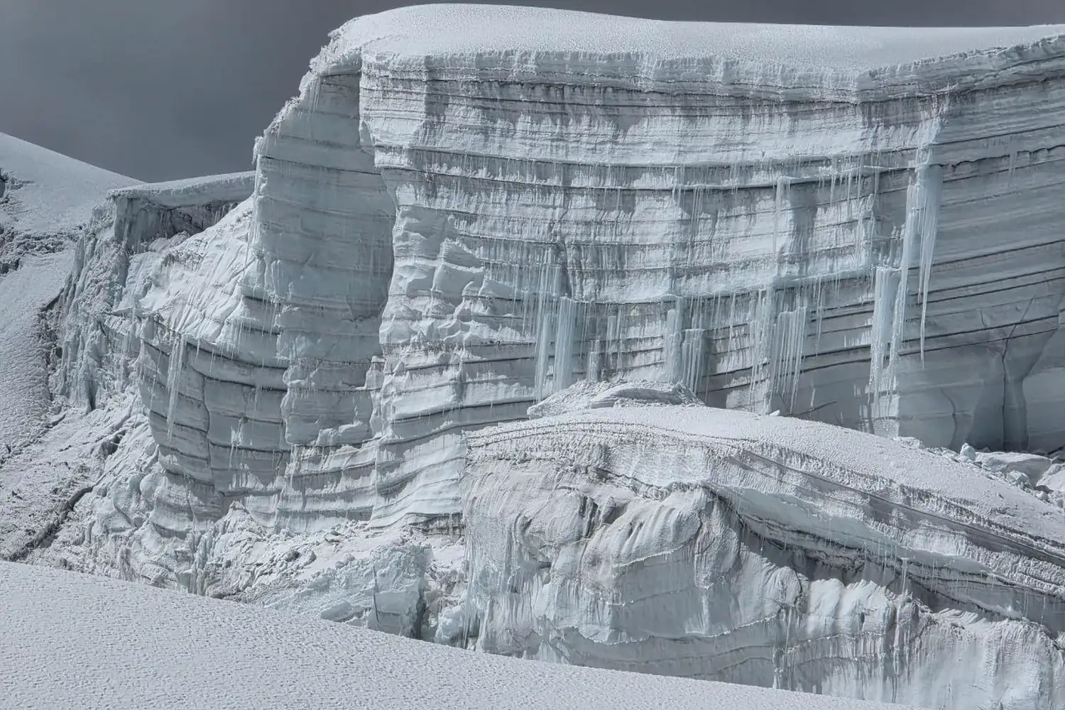 Pared de hielo con estratos horizontales oscuros y claros visibles